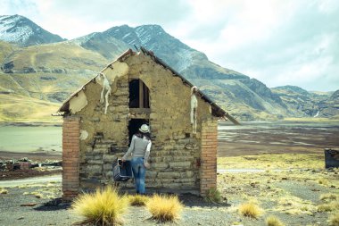 Uzun Kız, Ortaçağ 'da terk edilmiş küçük bir Adobe ve Tuğla Evi' ne bakıyor. Bolivya Altiplano 'sunda, Tavandan sarkan iki tane Lama cenini var.