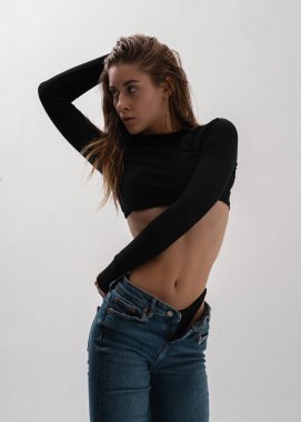 İç çamaşırlı, kot pantolonlu, beyaz arka planda poz veren seksi, şık esmer kadın. Baştan çıkarıcı zarif seksi kadın model portresi