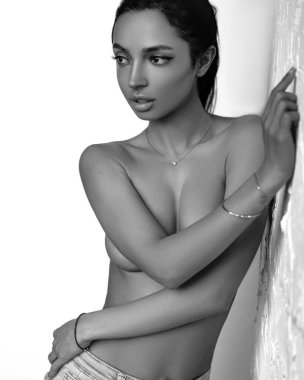 Esmer, güzel, üstsüz, mavi kot. Doğal cilt. Taş arkaplan