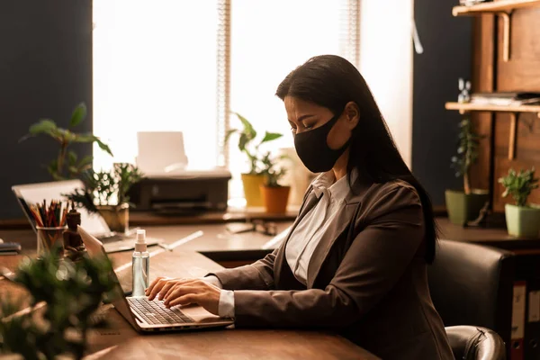 亚洲学生在家工作 女性家务事笔记本电脑 蒙面保护 工作场所 自由工作者 流行病概念 免版税图库图片