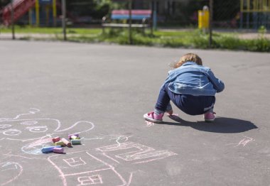Kız Kot ceket ile renkli tebeşirler çizer 