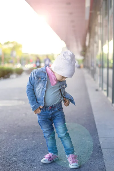 Une petite fille en jeans porte des spectacles dans la rue — Photo