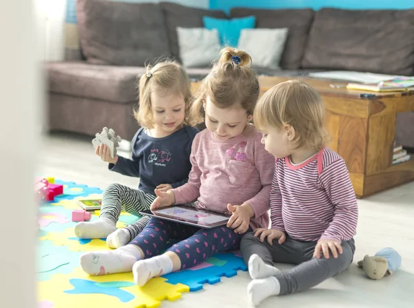 Tres hermanas pequeñas usan tableta en casa —  Fotos de Stock