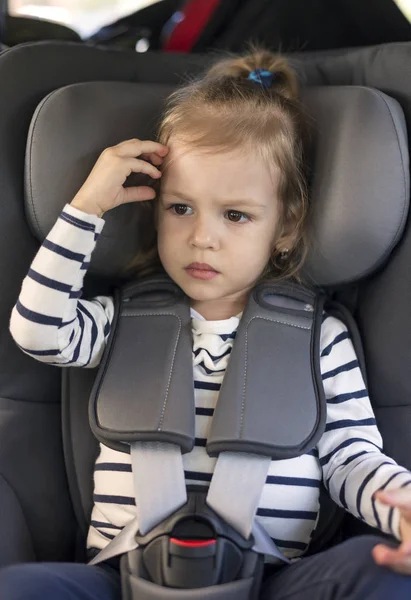 Linda niña pequeña en asiento de coche en el coche — Foto de Stock