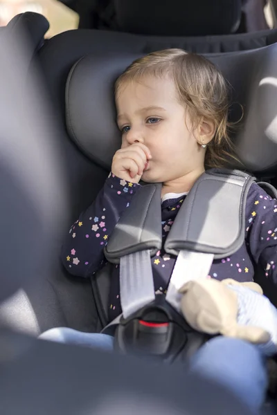 Lindo feliz niña pequeña en asiento de coche en el coche — Foto de Stock
