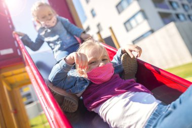 Doğu Avrupa 'daki mutlu çocuklar 19. karantina sırasında oyun parkında maskeyle oynuyorlar. Slovakya