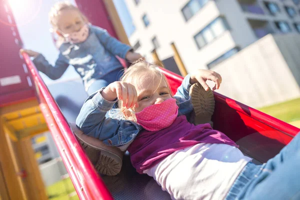 Happy children in eastern europe playing with face masks on playground during quarantine covid19. Slovakia