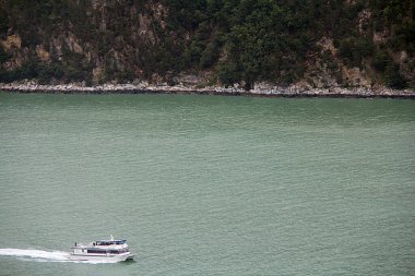 Yat tepelerin yakınında suda hareket ediyor.