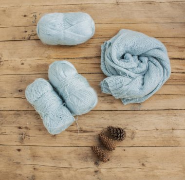 Örgü örüyorum. Ahşap bir masada duran iplik ve örgü kumaş.