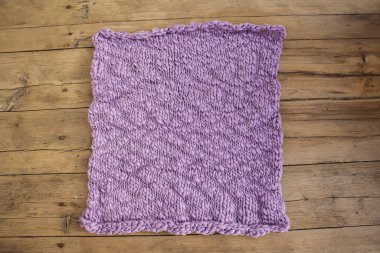 Ahşap tahtaların üzerinde menekşe rengi kare şeklinde örülmüş ketenler.