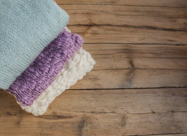 Yığınla örülmüş şeyler ahşap bir masanın üzerinde yatıyor..