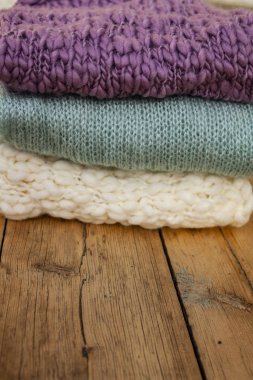 Yakın plan örülmüş üç farklı renk bir yığın halinde ahşap bir masanın üzerinde duruyor..