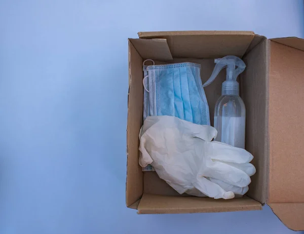 İçinde tıbbi maske, eldiven ve plastik şişede antibakteriyel bir madde olan açık bir posta kutusu var..