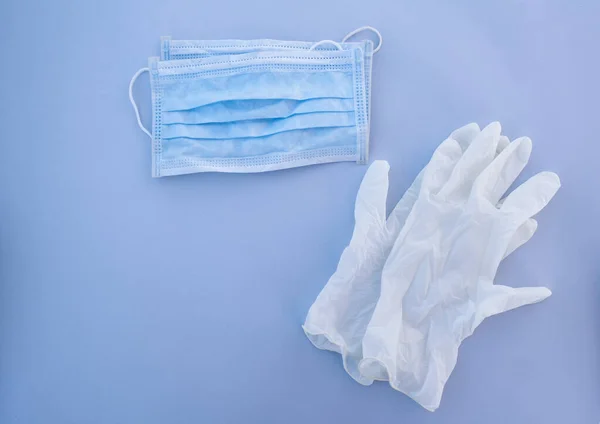 medical disposable mask and white gloves on a blue background. items of protection against coronavirus and other viruses