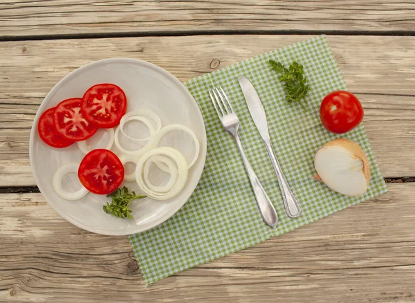 vegetables, a plate with chopped vegetables, a table knife and a fork on a tissue napkin on a table in the garden, top view.sports concept, diet, fitness, plan, healthy eating.