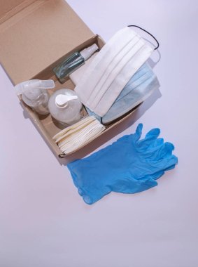 İçinde antibakteriyel maddeler, tıbbi maskeler ve kağıt havlular olan açık bir posta kutusu, kutunun yanında lateks eldivenler var.