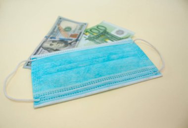 Sarı arka planda dolar, avro ve tıbbi maske.. 