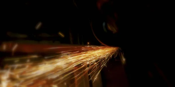 Metal kesim sırasında siyah bir arkaplanda ateş kıvılcımları, alevdeki sıcak yanma elementi. Seçmeli odak.