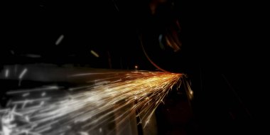Metal grinding on steel pipe with flash of sparks close up clipart