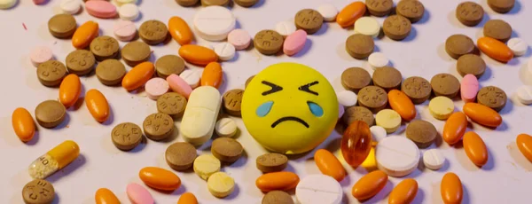 Emoji triste localizar no centro do monte de pílulas de medicina . Imagem De Stock