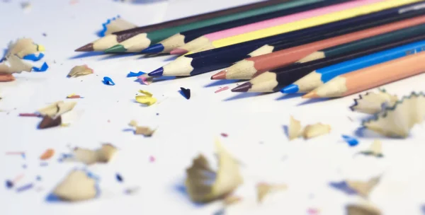 Close-Up Of Colored Pencils With Shavings On White Background . Copy space for text.