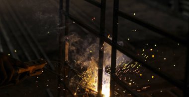 Koyu arkaplanda kıvılcımlar ve duman olan metal kaynaklama.