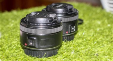 Yeşil çimenli arka plan üzerinde 50 mm 'lik iki asal lens. Kamera ve lensler için metin alanı için seçmeli odak kavramı.