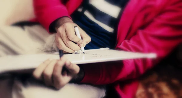 Young man writing with a white pen on a white page . Red jacket man writing. Concept for business. Blury and Selective focus with copy space for text.