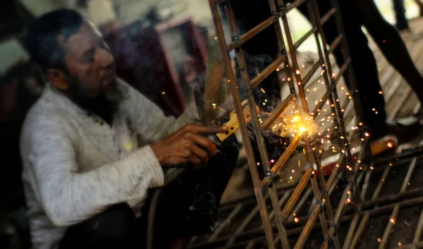 Dhaka, Bangladeş-26 Şubat 2020: Bir atölyede çalışan kaynakçı metal yapılar üretir. Kaynak yapmaktan kıvılcımlar uçuşuyor.