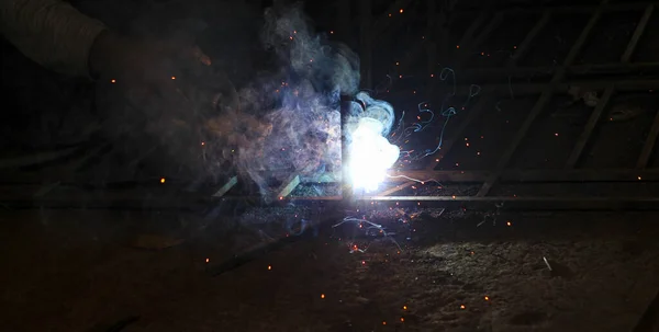 Metal kaynaklama. Elektrikli ısıtmadan kıvılcımlar. Atölyede çalış. Malzemelerin güvenilir şekilde birleştirilmesi. Demirin üretimi. Metal ustasının işi..