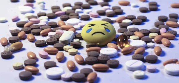 Dhaka,Bangladesh-February 26 , 2020 : Heap of various kinds medicine pills on white background with a sad emoji.