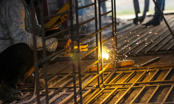 Metali fabrikada kıvılcımlarla kaynak yapan işçilerin kısmi görünümü. Metin için metin alanı ile seçmeli odak.