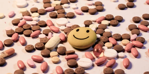 Renkli multi vitamin hapları, haplar ve kapsüllerin geçmişi. Üzgün bir emojiyle.