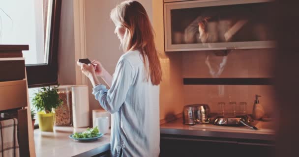 Mulher usando telefone na cozinha — Vídeo de Stock