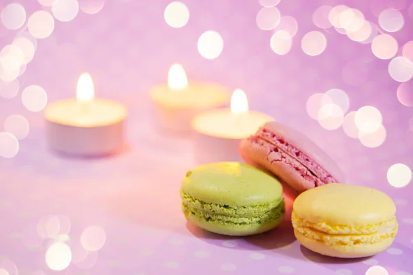 Fresh French Macaroons with candles on romantic pink background