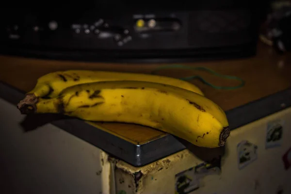 an overripe banana is lying on an old refrigerator.