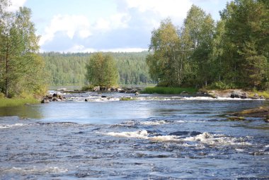 Köprüden ağaçlara kadar engebeli kayalık nehrin yolunda büyüyen manzarayı izle. Beyaz köpüklü mavi ile beyaz bulutlu mavi arasında yeşil ağaçlar. 2014 'te Rusya' nın Karelia Cumhuriyeti 'nde çekimler