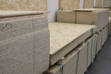 Alışveriş sırasının başında toptan bir inşaat mağazasında istiflenmiş kontrplak kağıtları. Dükkan ışıklarının altında çekilmiş. Daha fazla çalışma için bir arkaplan ya da bağımsız bir illüstrasyon olarak hizmet verebilir.