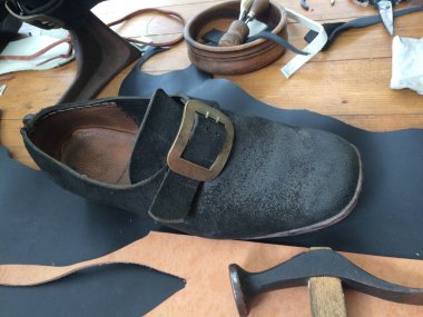 Üretimi için objelerin arka planında metal tokalı büyük bir deri ayakkabı. Doğal gün ışığında taşınabilir fotoğraf.