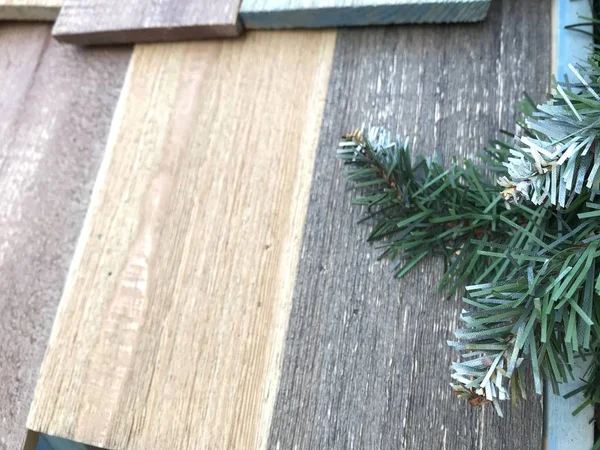 多色の木製の板と人工的なクリスマスツリーのいくつかの緑の枝のファジィな質感 自然光の中のモバイル写真 — ストック写真