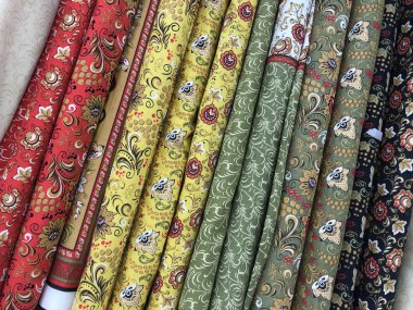 Texture of diagonal rolls of fabric in bright colors in folk style. Mobile photo with store lighting. 
