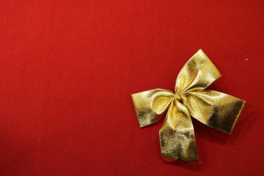 Red textile background with a gold bow with curved edges in the lower right corner.