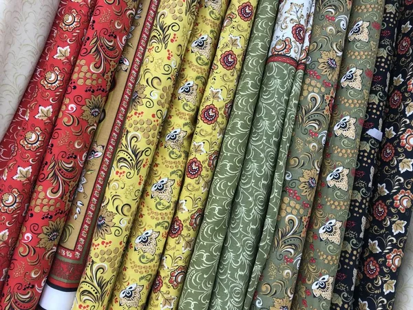 Texture of diagonal rolls of fabric in bright colors in folk style. Mobile photo with store lighting. 