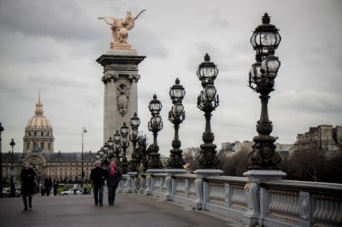 Paris 'te Pont Alexandre III' te yürüyen bir çift.