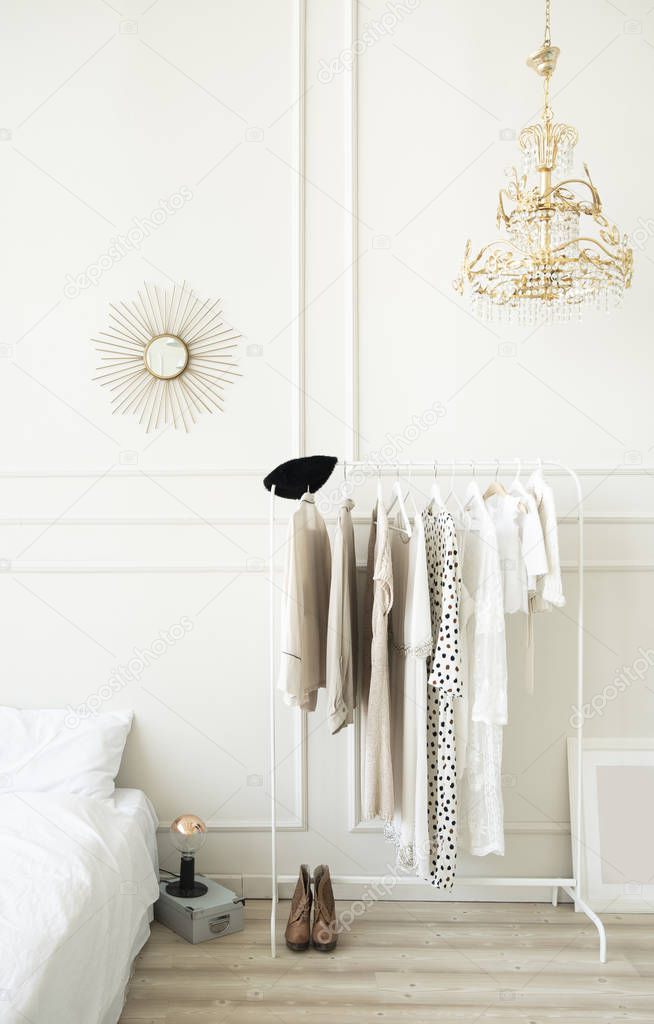 Fashionable bright bedroom interior. Hanger with women's clothing. Women's bedroom