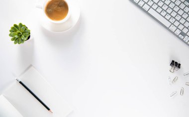 Üst kattaki ofis masasında yatıyordu. Çalışma alanı boş pano, ofis malzemeleri, kalem, yeşil yaprak ve beyaz arka planda kahve fincanı. Boşluğu kopyala.