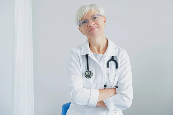 Beyaz arka planda kadın doktor portresi. Bir kadın doktor gülümsüyor ve kameraya bakıyor. Profesyonel tıp.