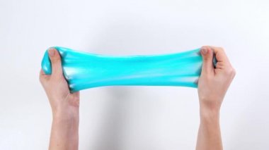 Çamurla oynamak, eğlence ve stres atmak için yapışkan maddeyi germek. Yaklaş ve üst görünümde kadın eli mavi parlak balçık tutuyor, sıkıyor..