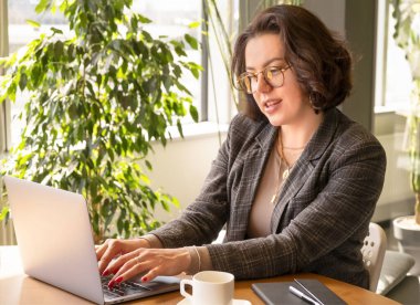 Başarılı bir iş kadını bilgisayar sörfü internetinde yazı yazıyor ve uzak işlerden zevk alıyor. Müşteriye Millennial Daktilo yanıtı, sadece ofiste bilgisayarla çalışmak.