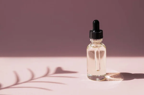 Skin care essence oil dropper glass bottle pink background. Hydrating serum, vitamin for face skin.